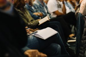 Several people with Bibles open and holding notebooks and pens.